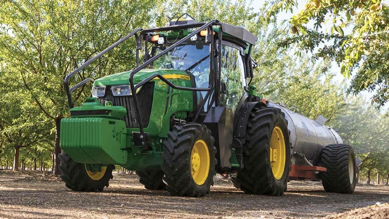 Person operating a 5105EN Tractor with a StarFire™ 7500 Receiver down an orchard row.